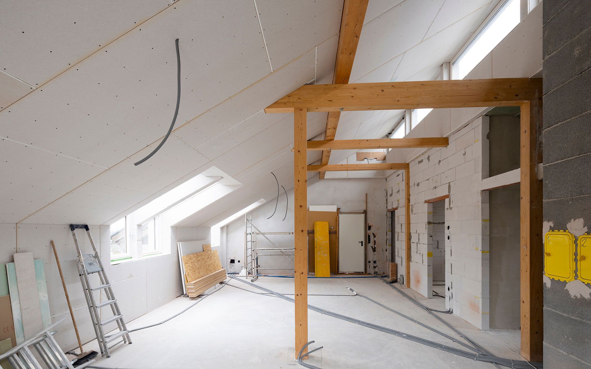 Interior of a room under construction with wooden beams and drywall. 
