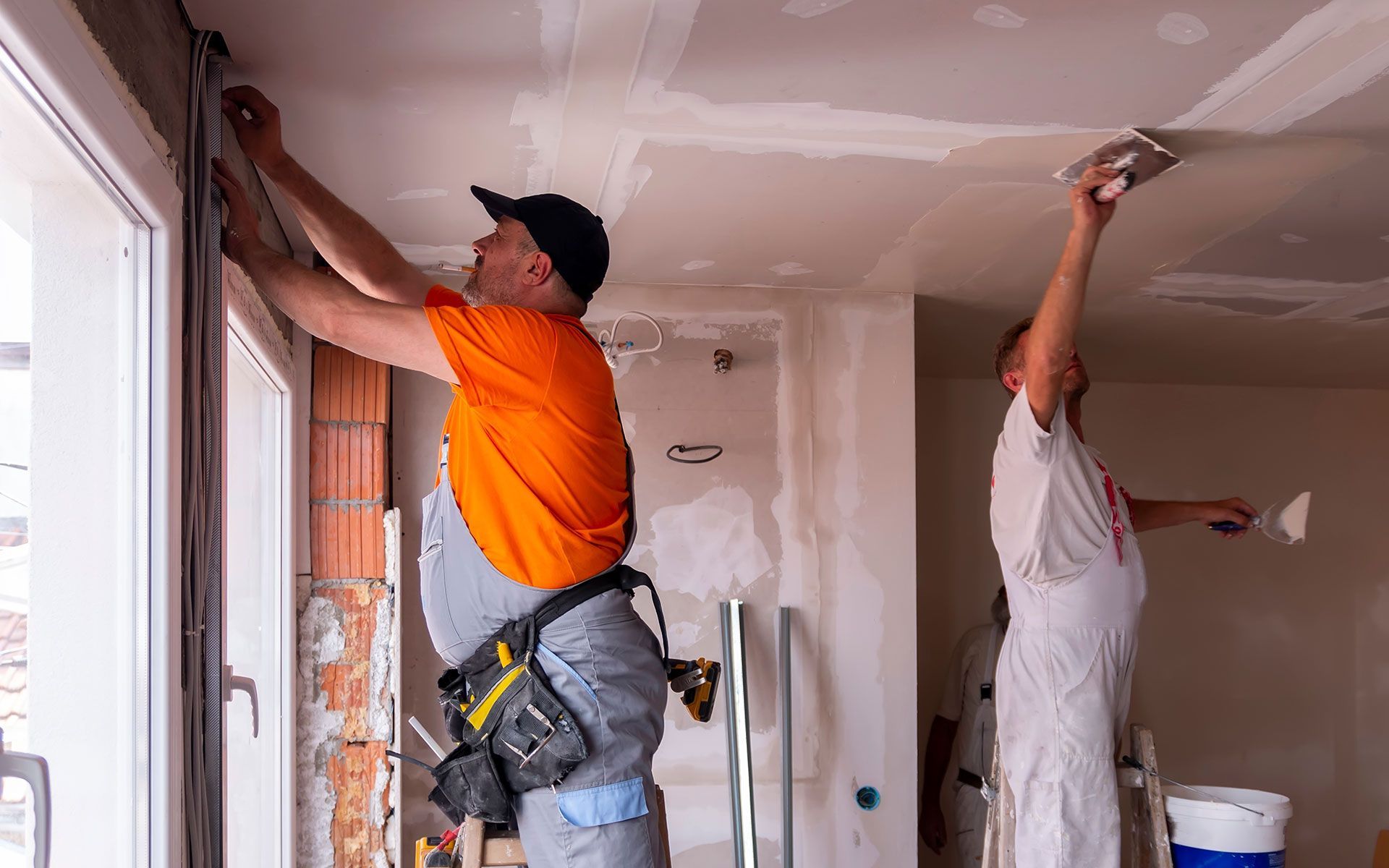 Two construction workers renovating a room.