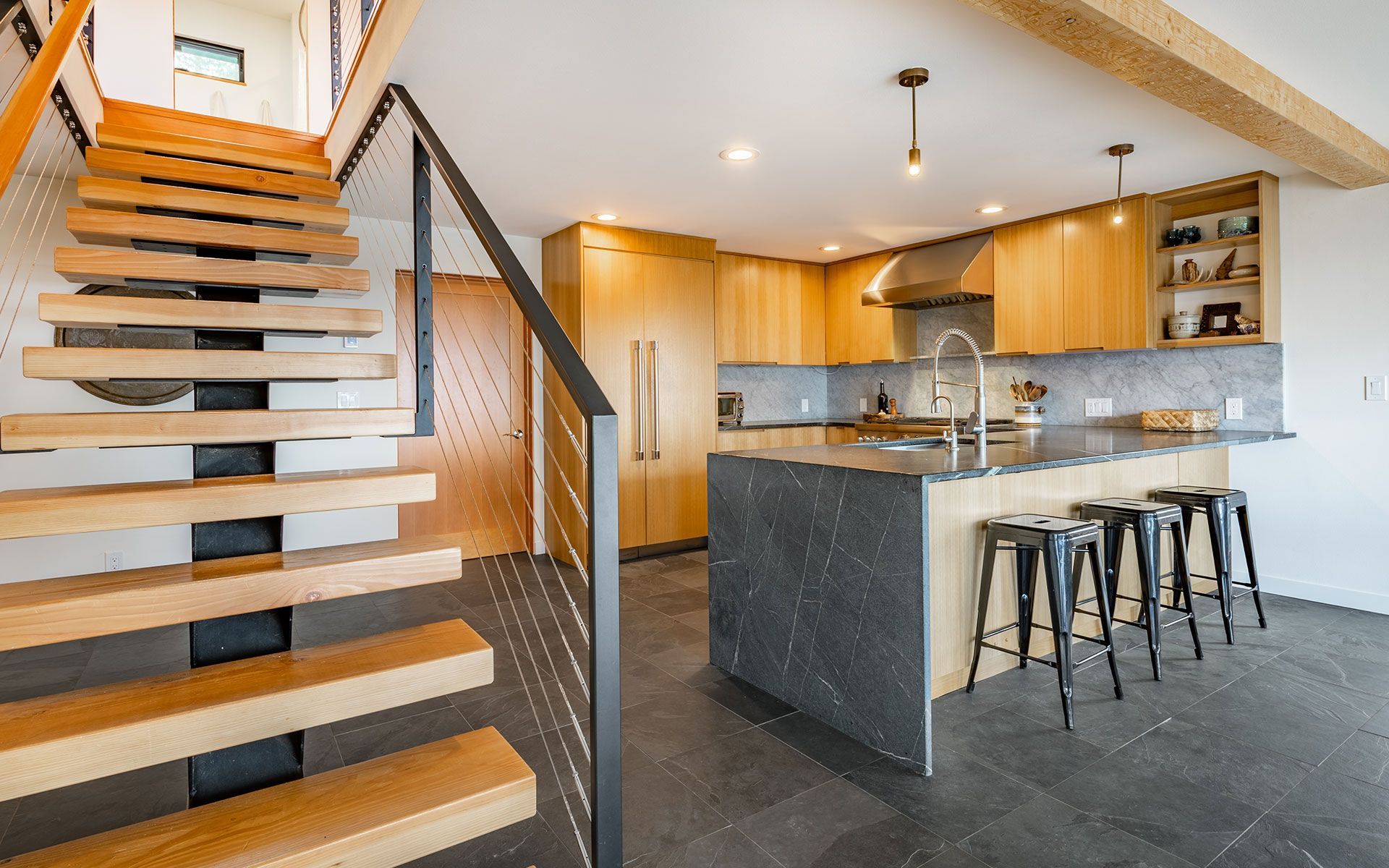 Modern kitchen with light wood cabinets, dark gray island