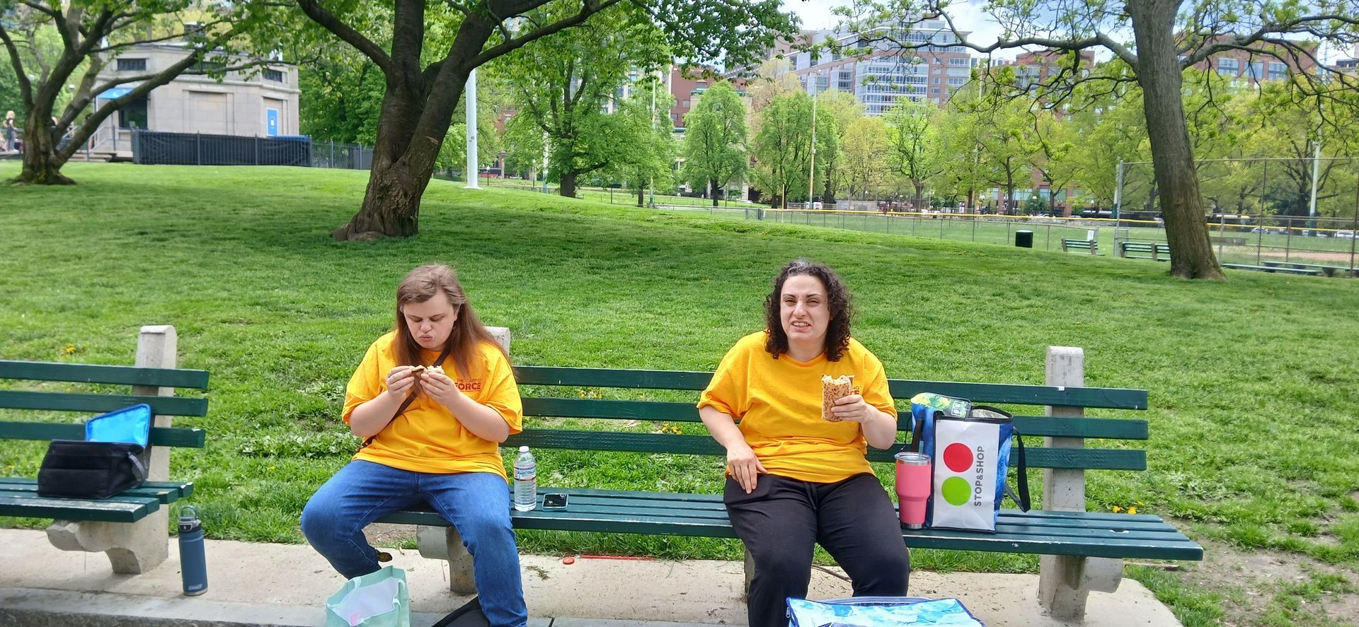 A group of BFAIR individuals in yellow shirts eating their lunch at the Caring Force Rally in Boston