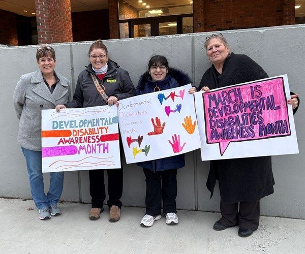 BFAIR staff and program participants standing outside with signs for disability awareness