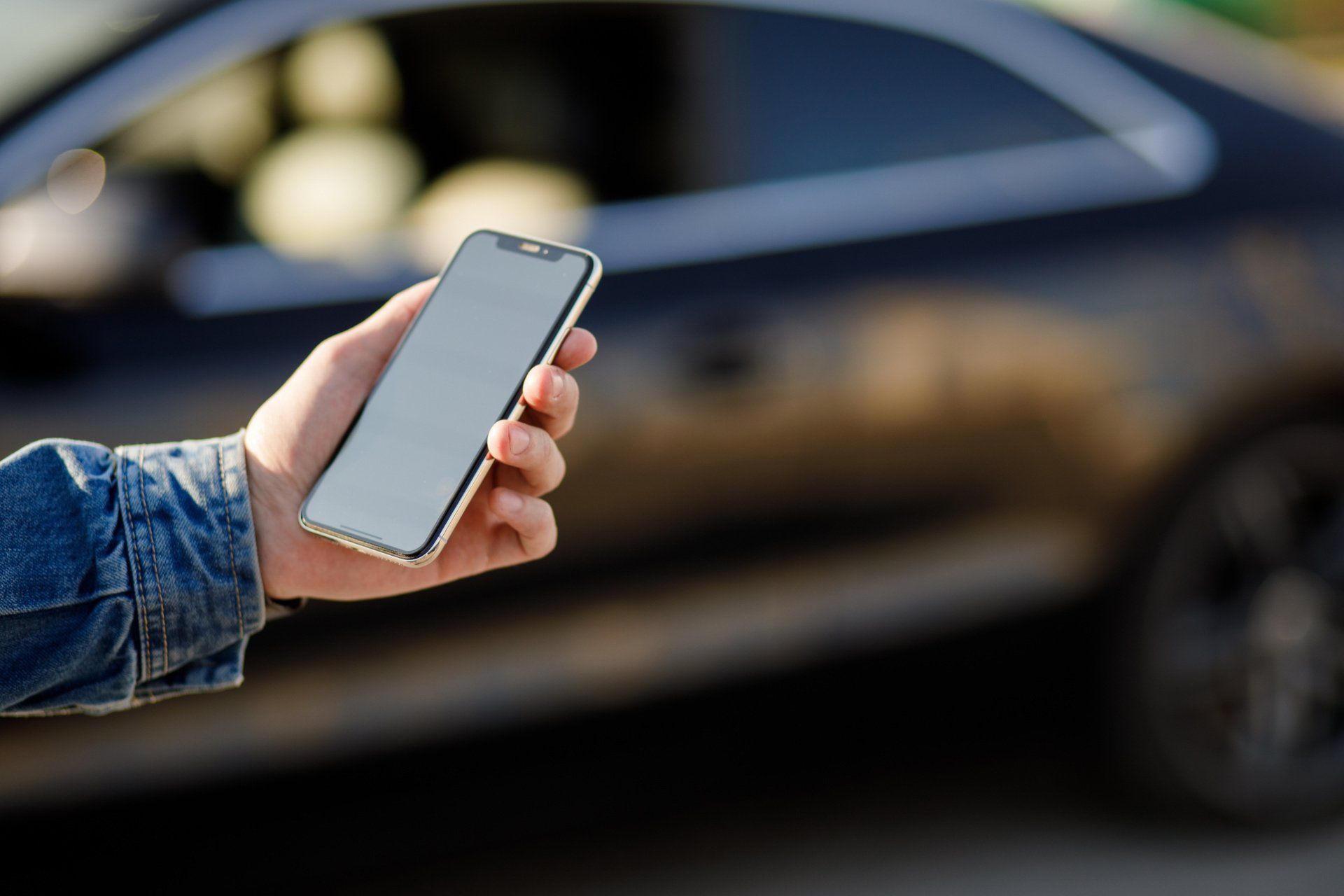 person holding a smartphone in front of a car