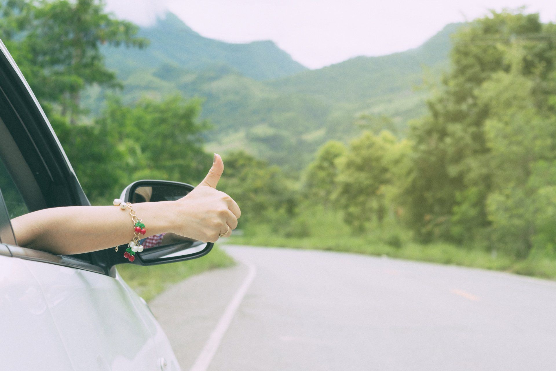 thumbs up out of car window while driving
