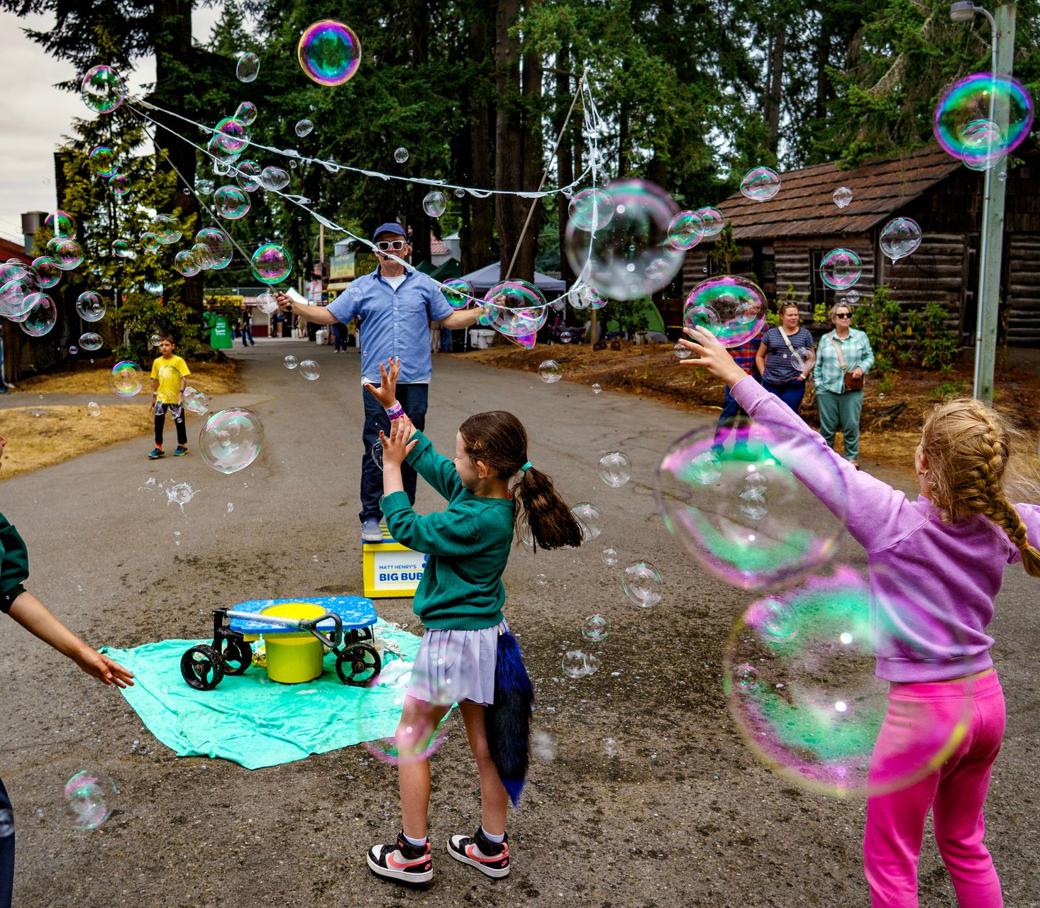 A man is making a giant soap bubble in front of a group of children.