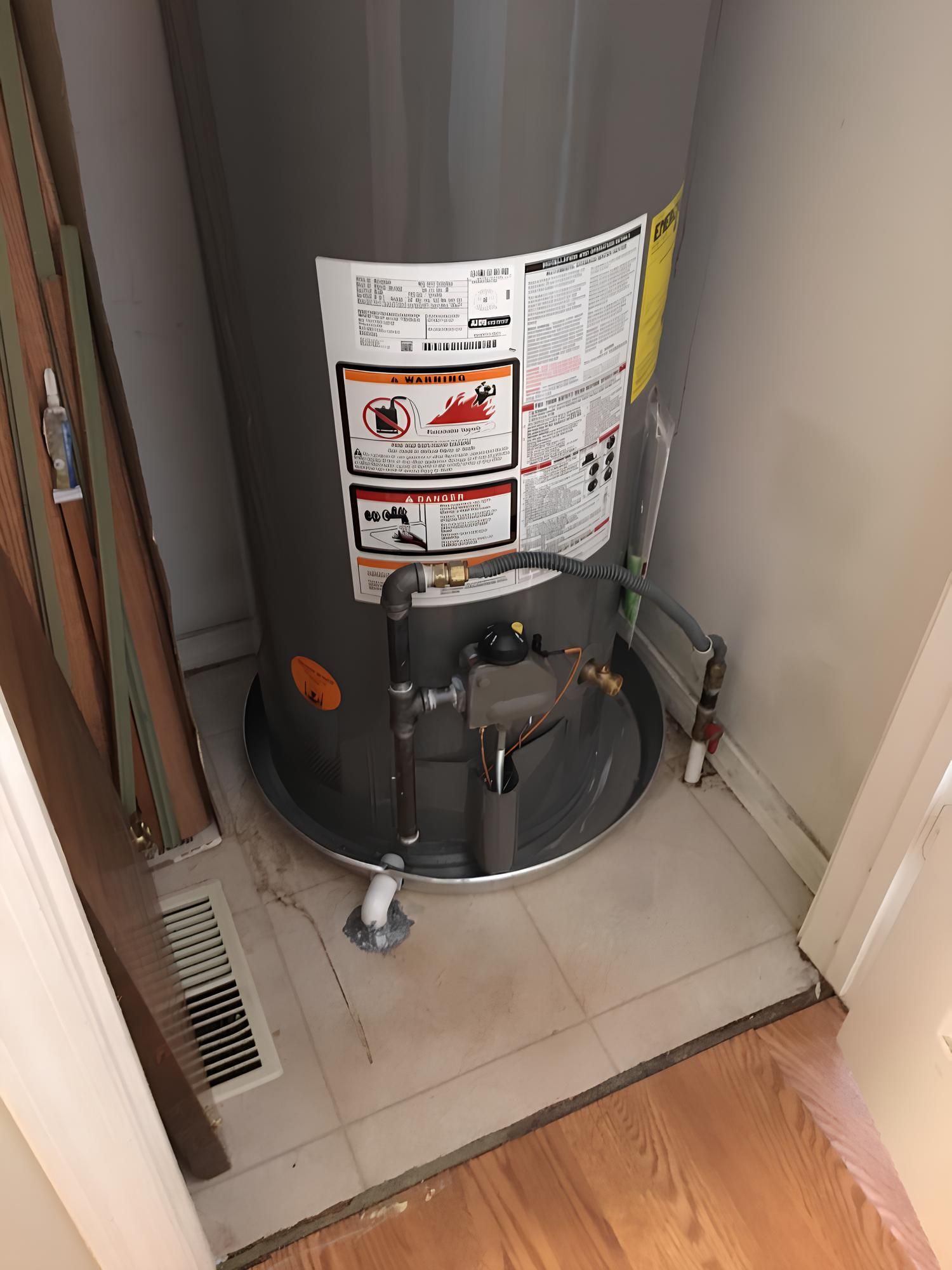 Furnace and water heater in a basement. Grey metal units against white walls, with pipes.