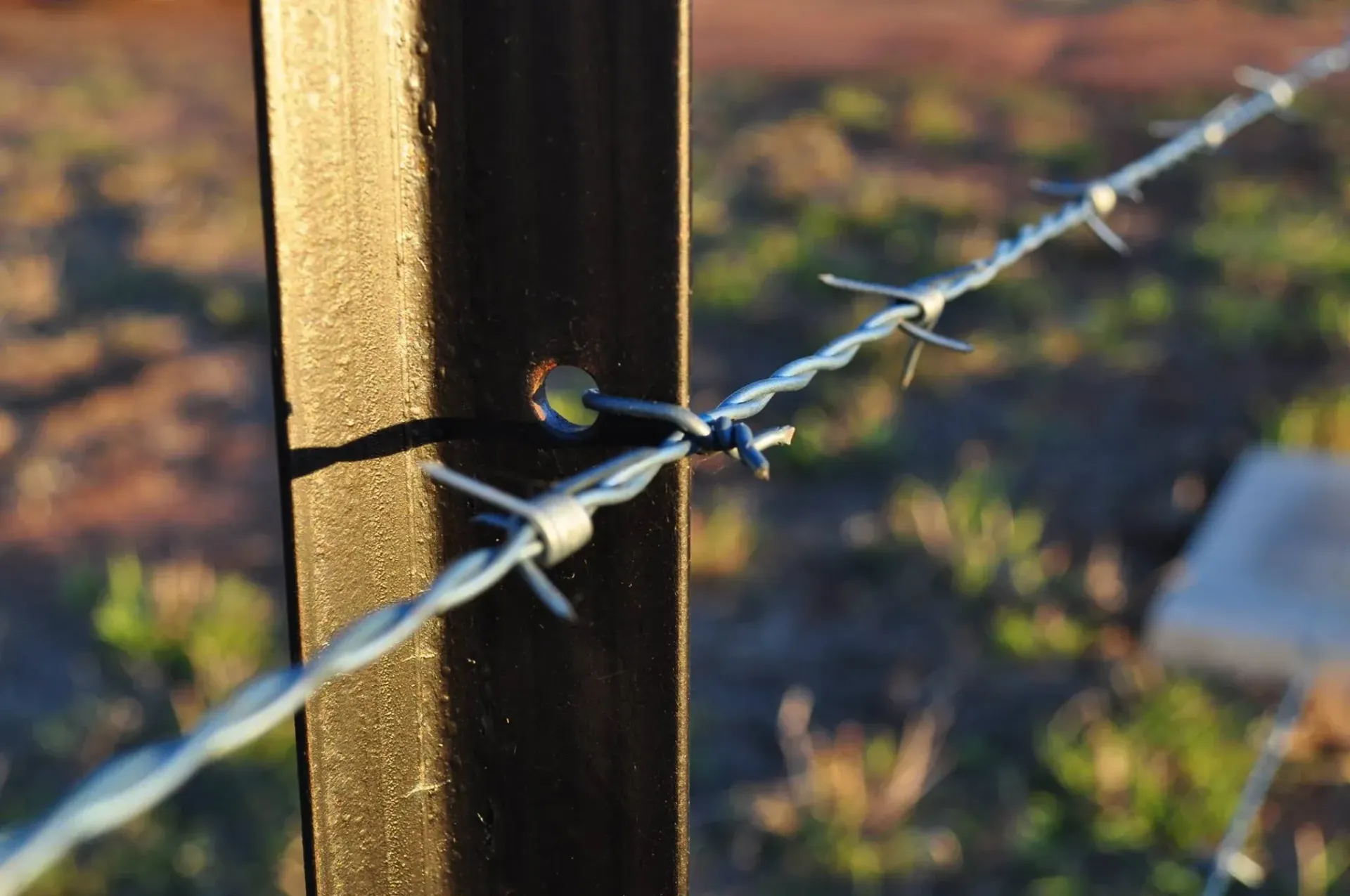 A barbed wire fence is attached to a wooden post