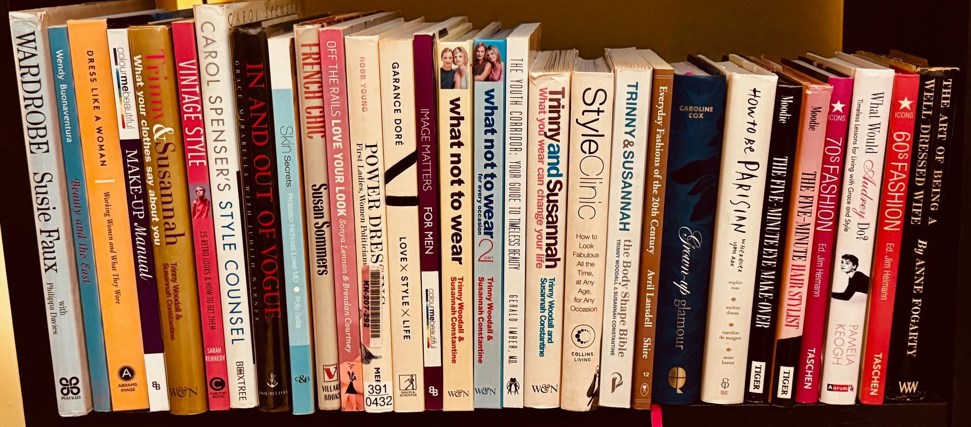 A row of books with varied colorful spines lined up on a dark shelf.