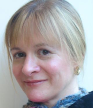 KatrinaRobinsonWriter. P2YL. Close-up portrait of a smiling person with short blonde hair against a light background