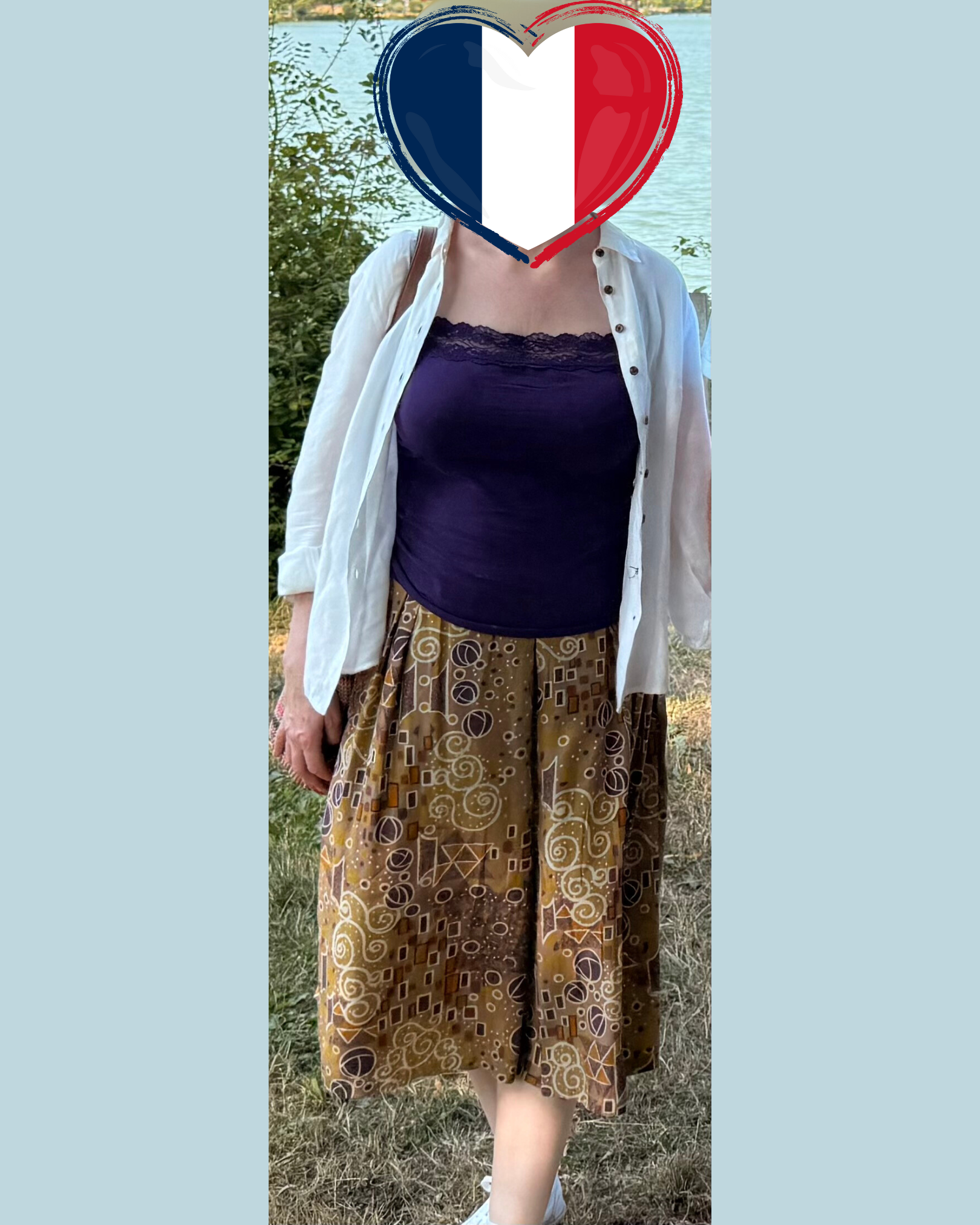 A person wears a dark purple tube top, a white button-down shirt, and a brown patterned midi skirt outdoors.