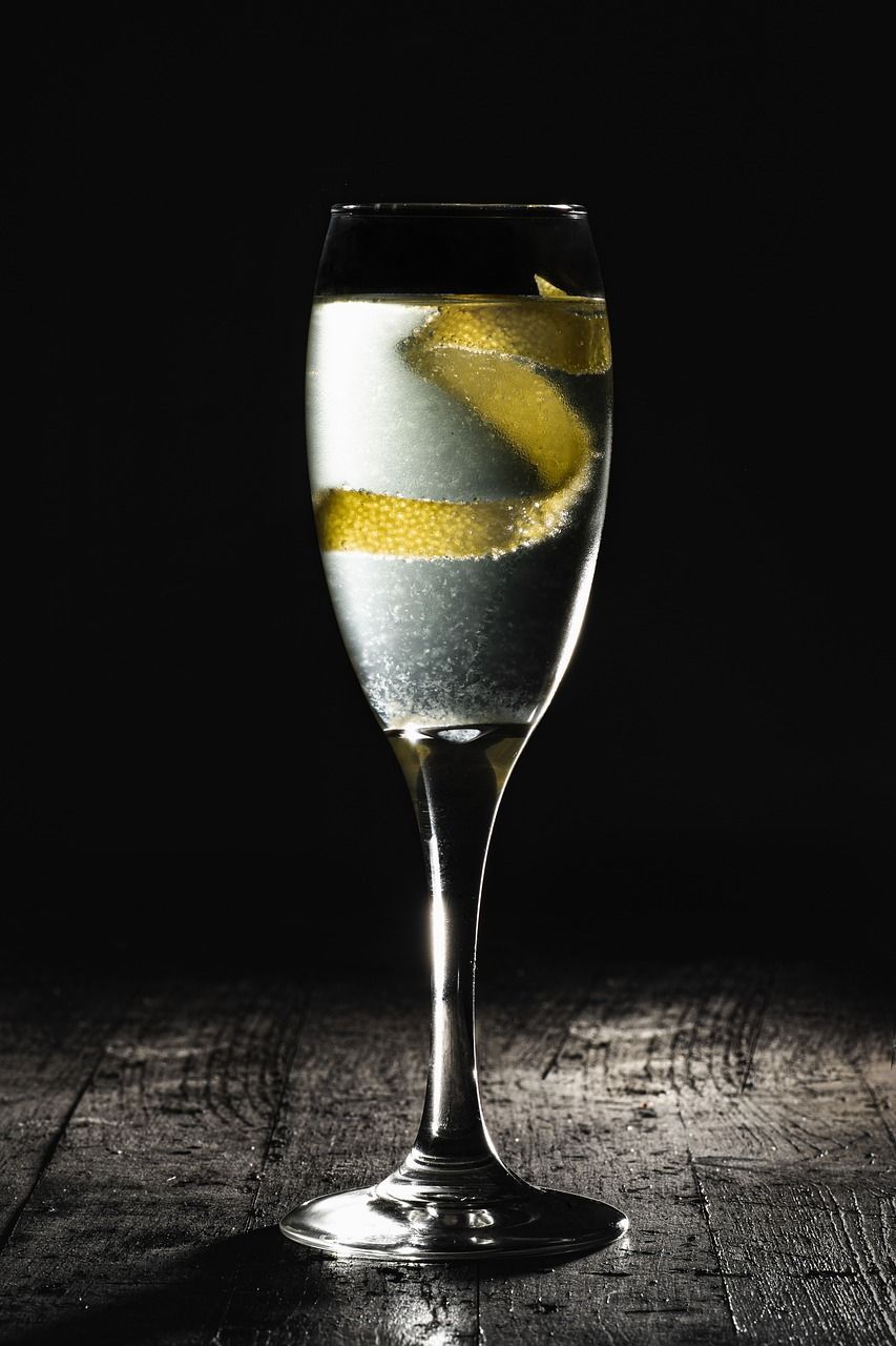 A chilled cocktail in a stemmed glass with a lemon twist, set on a rustic wooden table against a dark background.