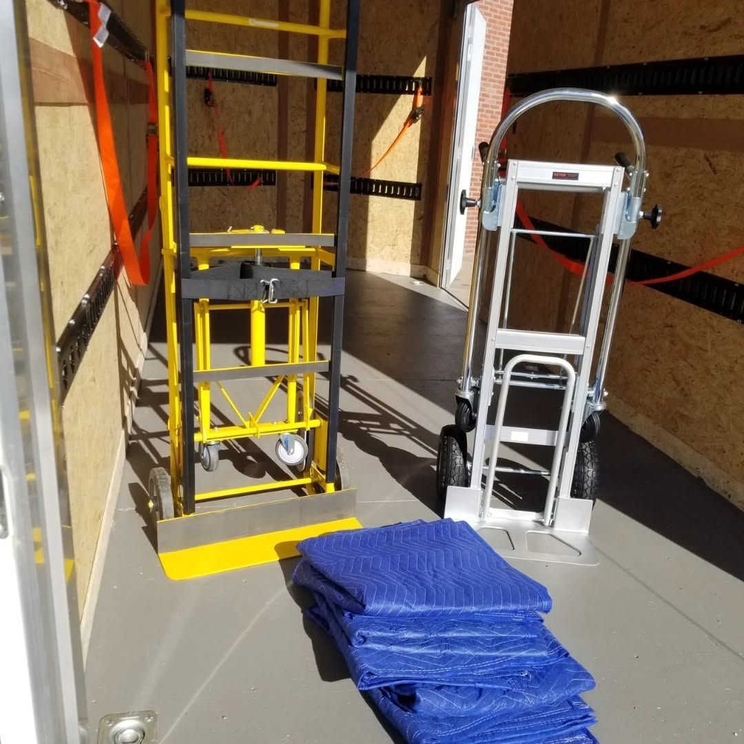 Yellow shelving unit and a white hand truck in a narrow storage corridor, with a blue folded tarp on the floor.
