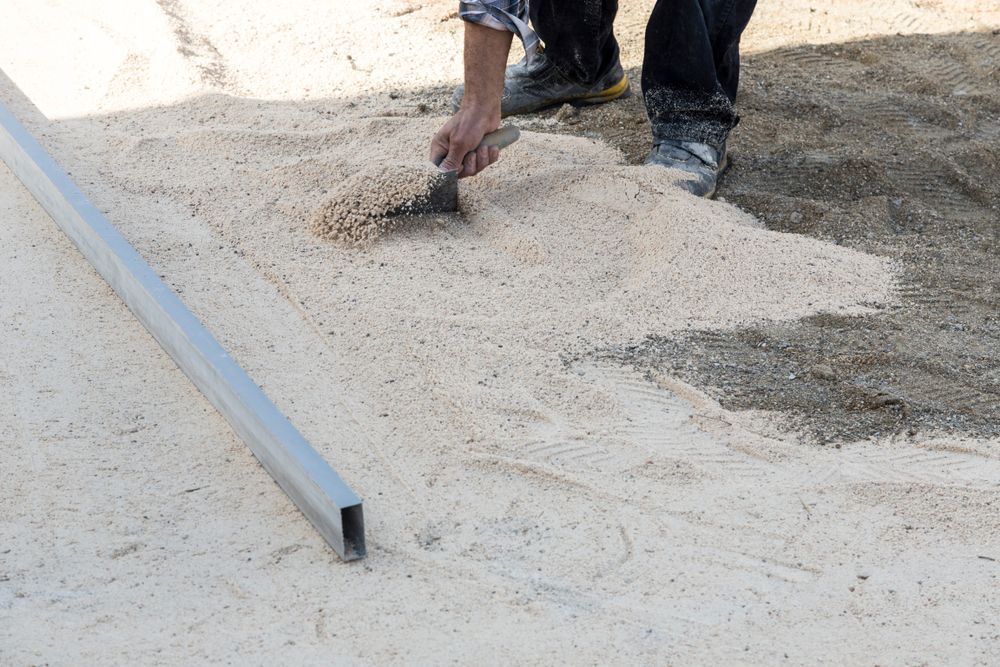 Person Using a Trowel to Spread Light-colored Sand — Australian Sandstone Products In Helidon, QLD
