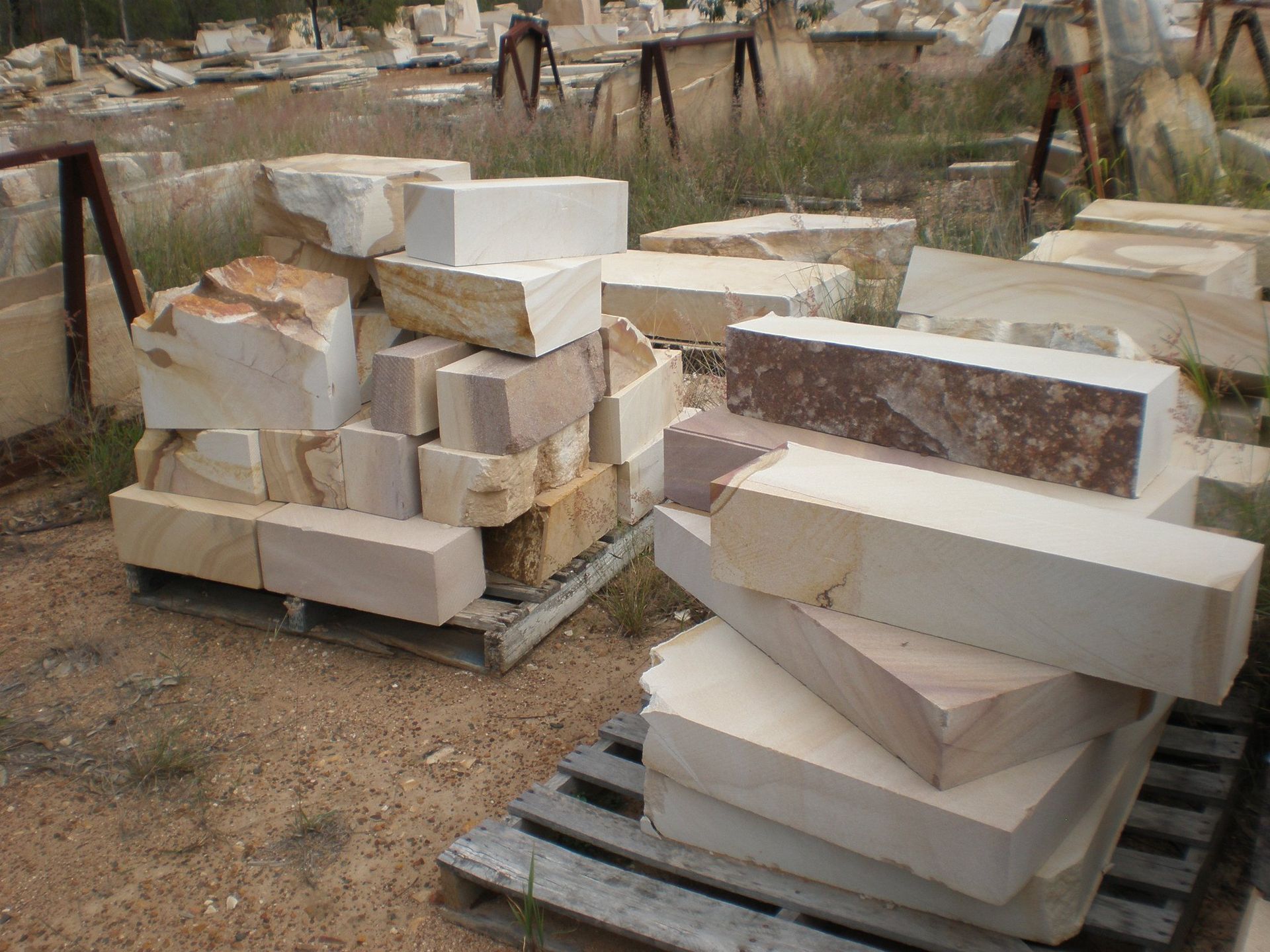Pile of Beige and Brown Stone Blocks on Wooden Pallets Outdoors — Australian Sandstone Products In Helidon, QLD