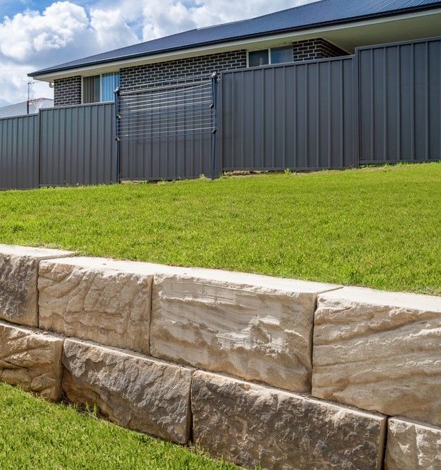 Stone Retaining Wall Supporting a Grassy Lawn — Australian Sandstone Products In Helidon, QLD