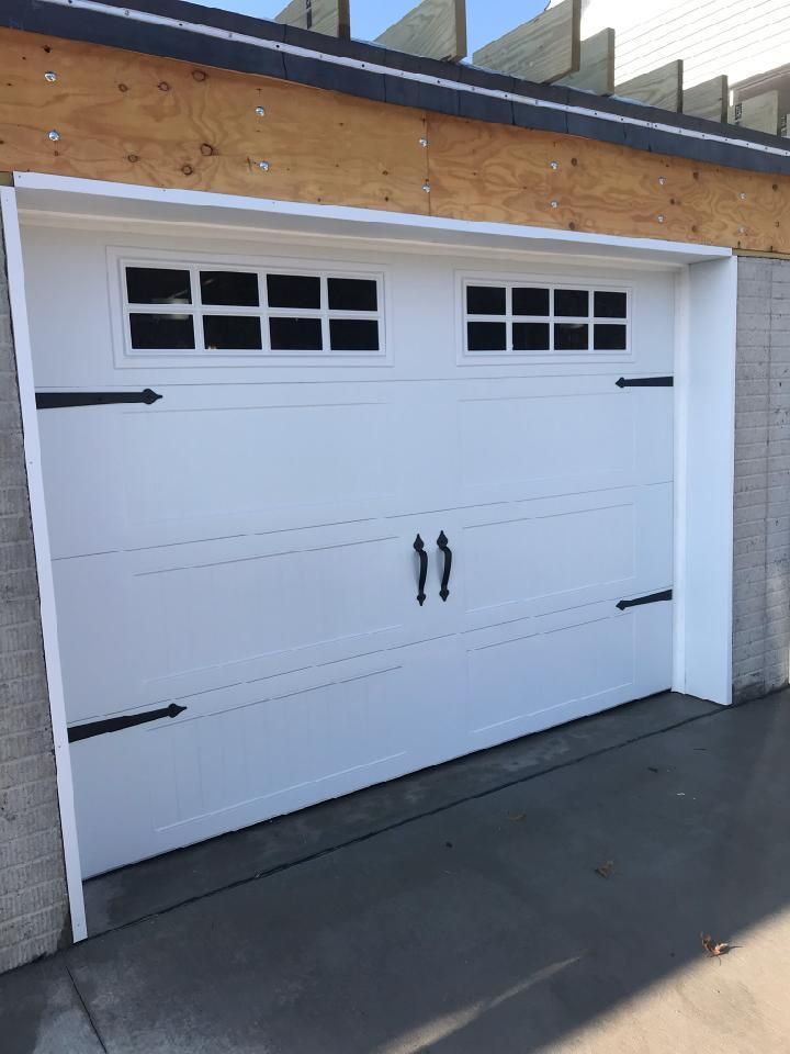A white garage door with black handles and windows