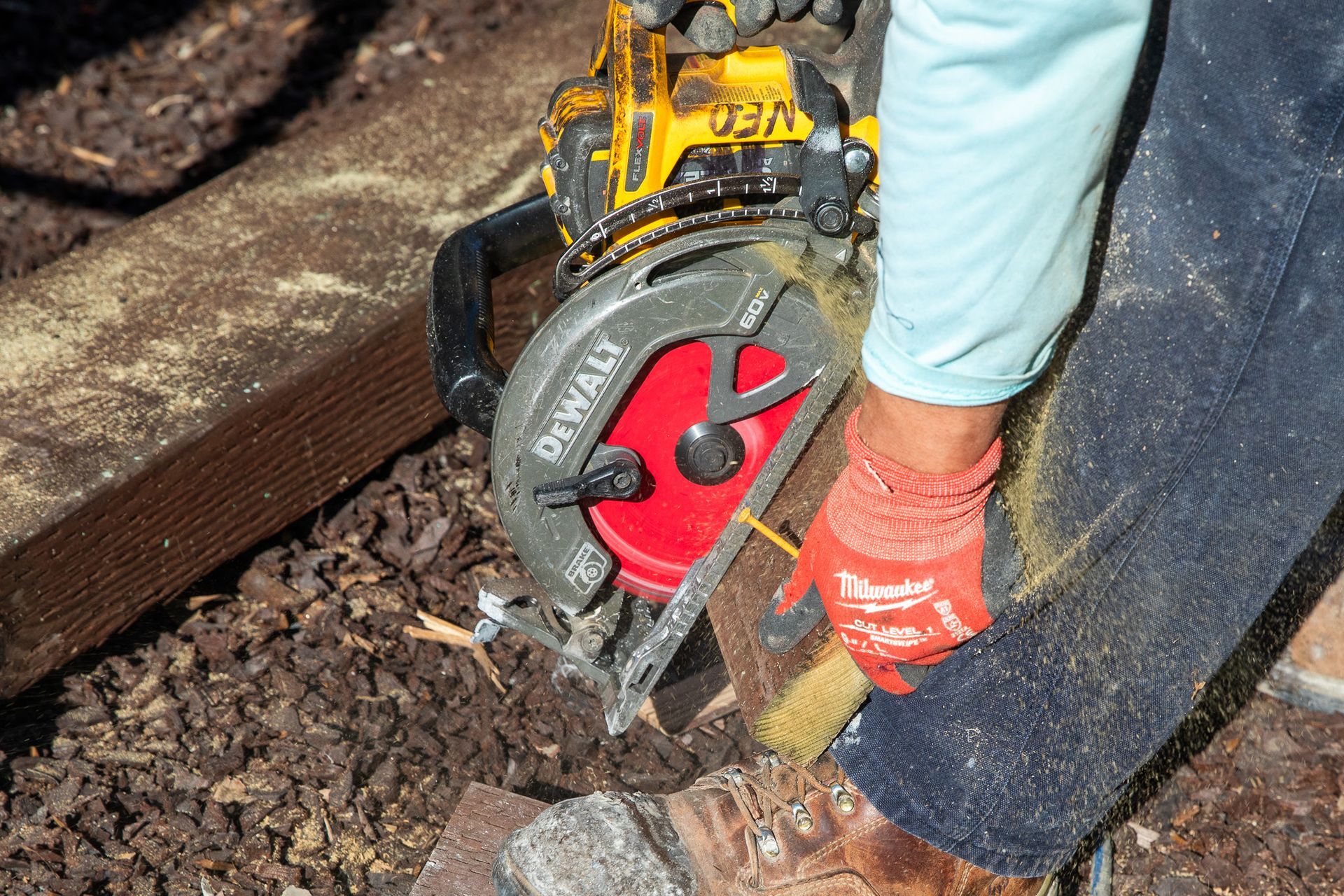 Person using a yellow and black circular saw to cut a wooden plank.