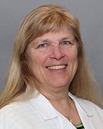 A woman in a white lab coat is smiling for the camera.