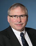 A man in a suit and tie is wearing glasses.