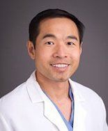 A man in a white lab coat is smiling for the camera.