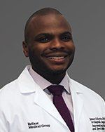 A man in a lab coat and tie is smiling for the camera.