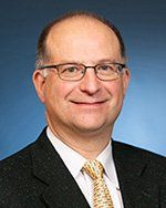A man in a suit and tie is smiling for the camera.