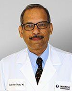 A man with glasses and a mustache is wearing a white coat and tie.