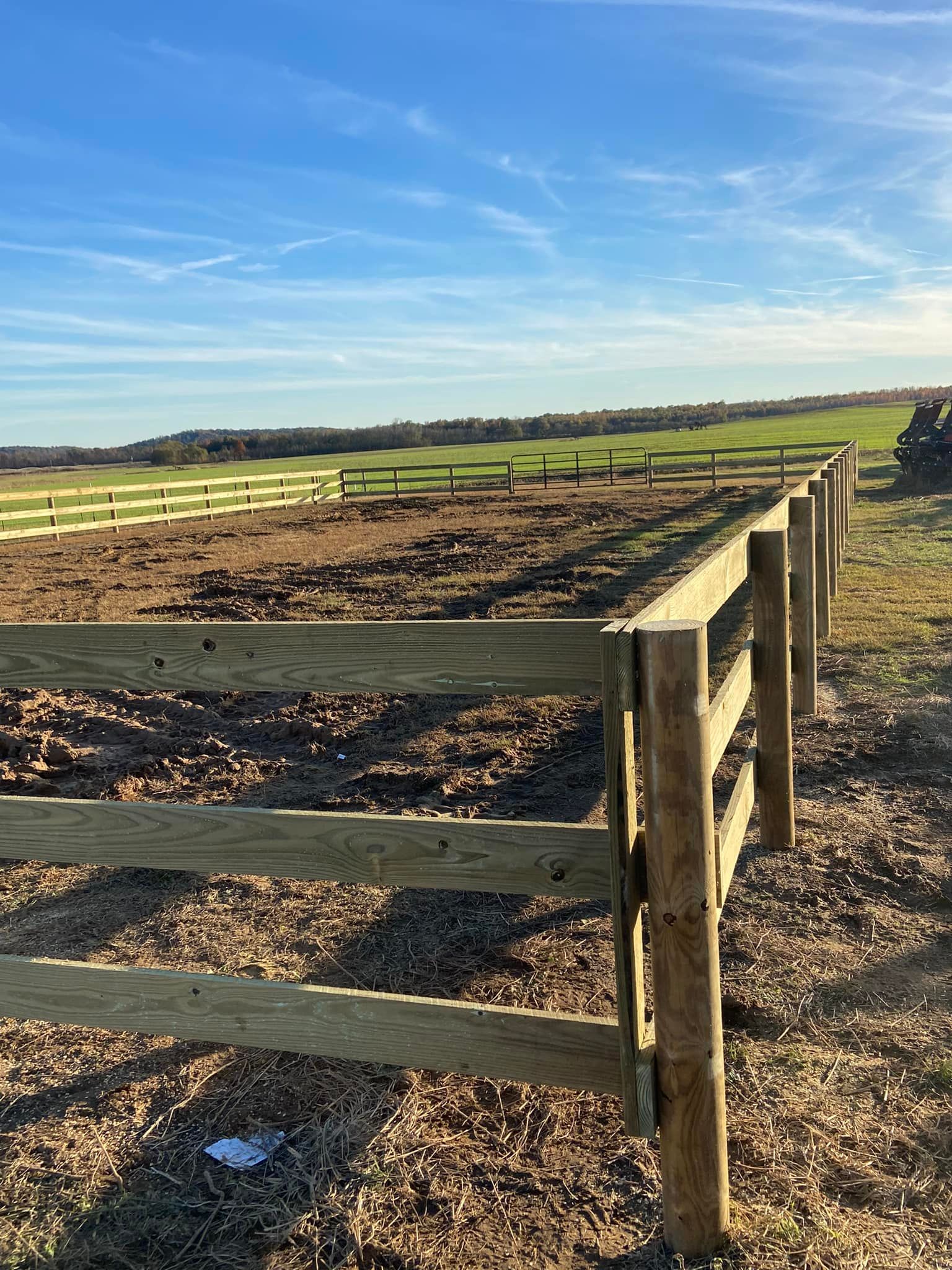 Wooden fence in a field on a sunny day with a blue sky.