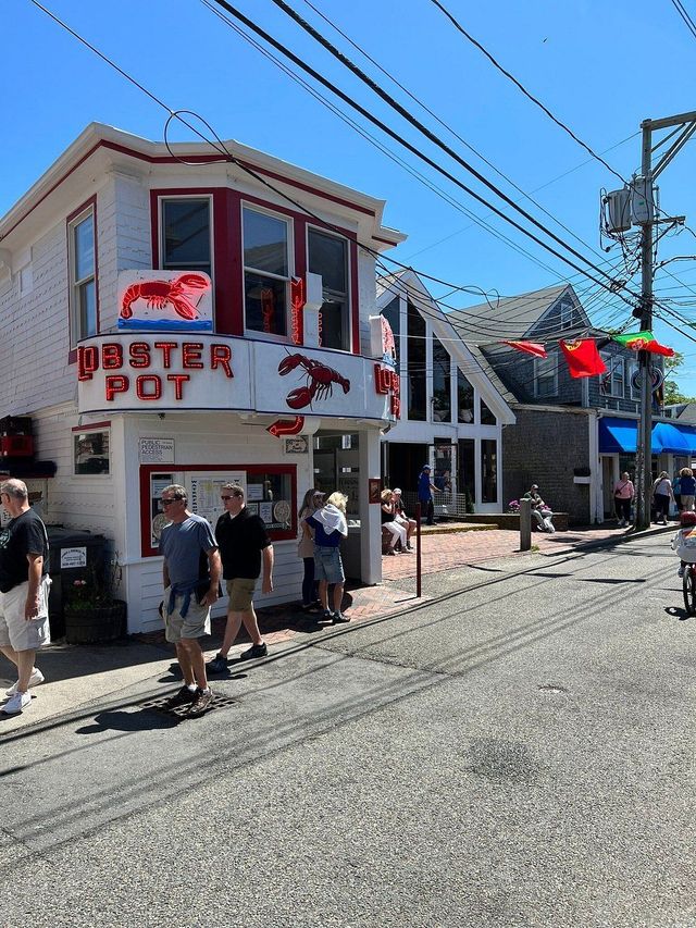 A group of people are walking in front of a lobster pot restaurant