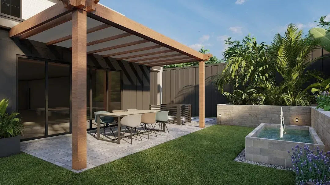 Modern patio with dining table under a pergola, lawn, and a small fountain pool beside tropical plants