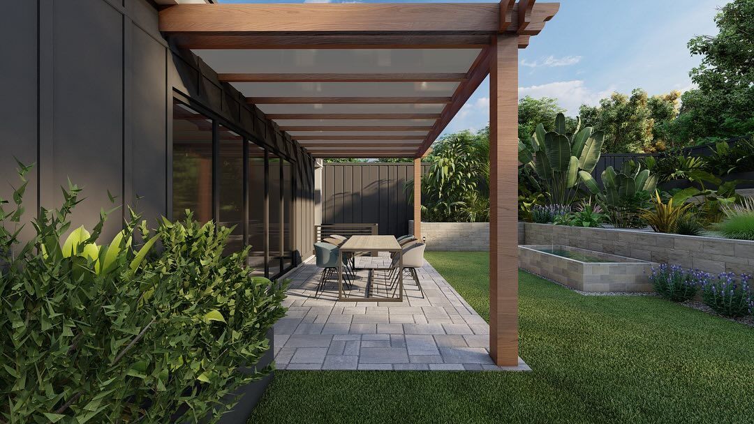 Modern patio with wooden pergola, outdoor dining table, pavers, and lush greenery.