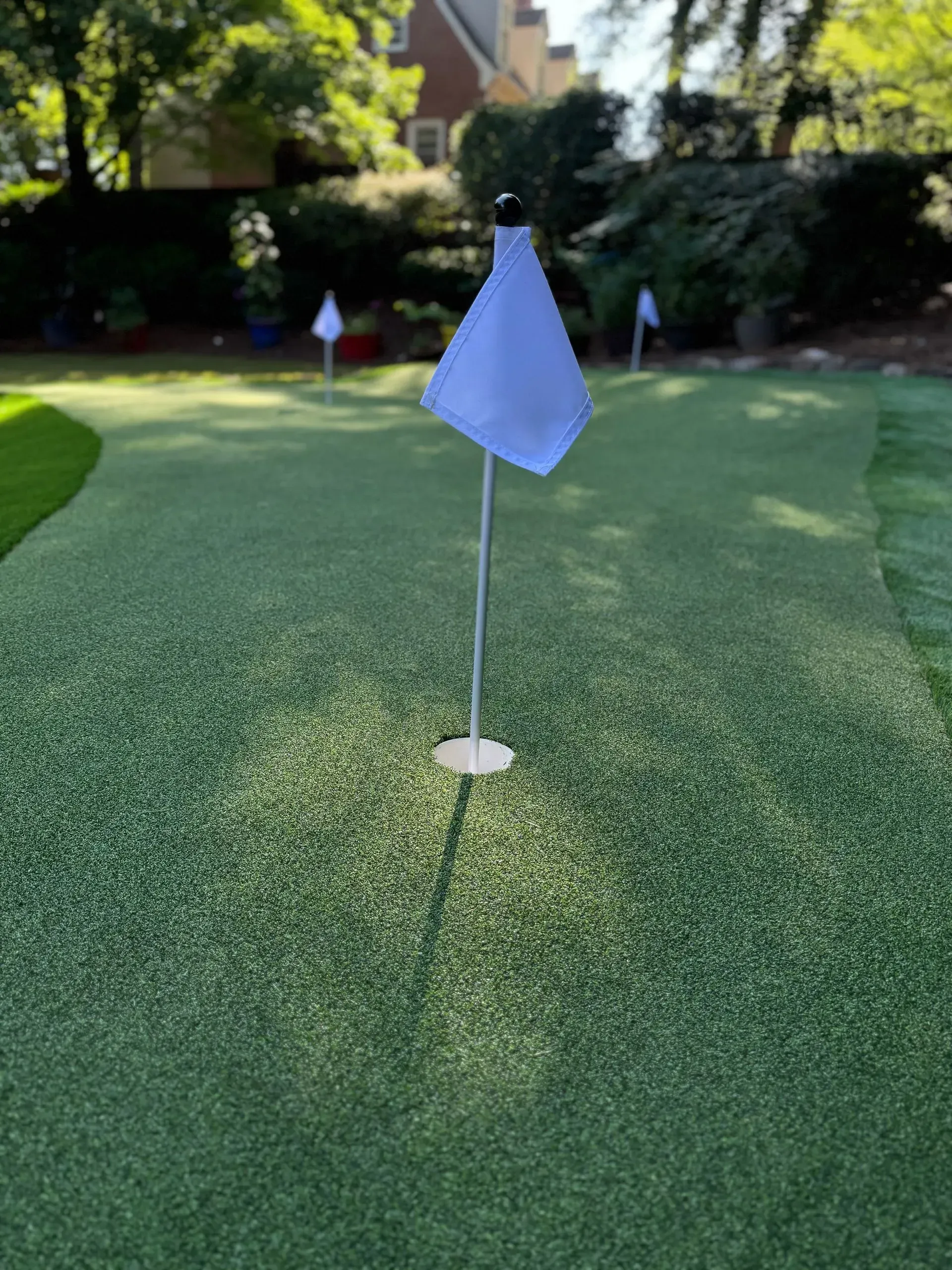 Blue golf flag on a putting green with a red marker in the background
