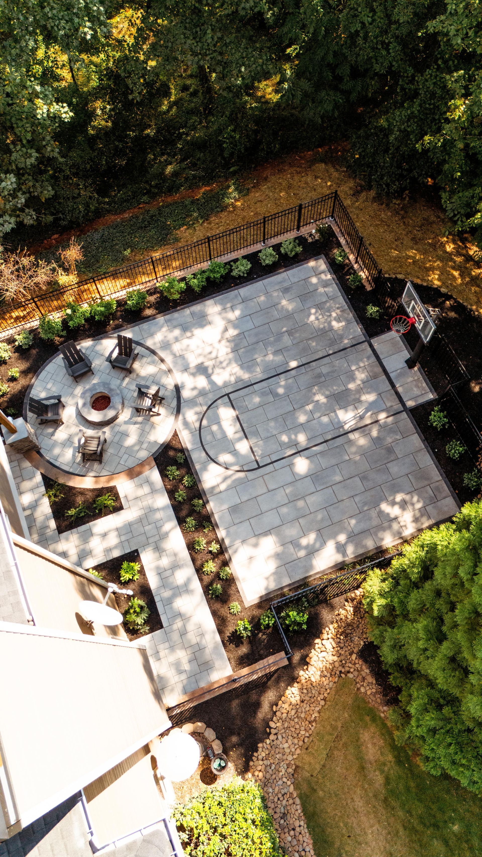 Aerial view of a patio with a round table, chairs, and a large tiled seating area surrounded by trees.