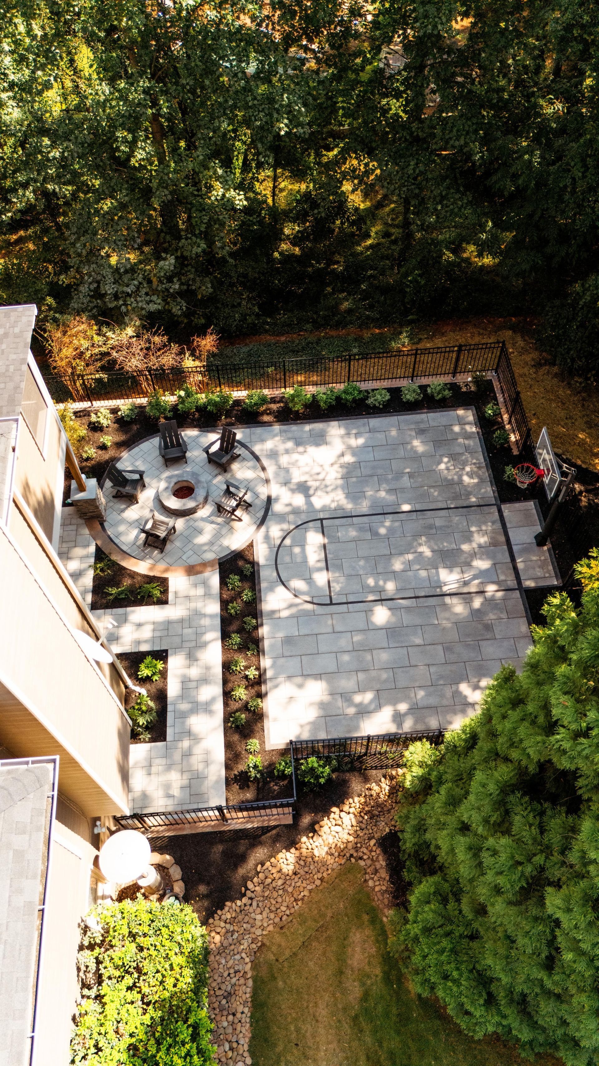 Aerial view of a small stone patio with outdoor seating, surrounded by trees and greenery.