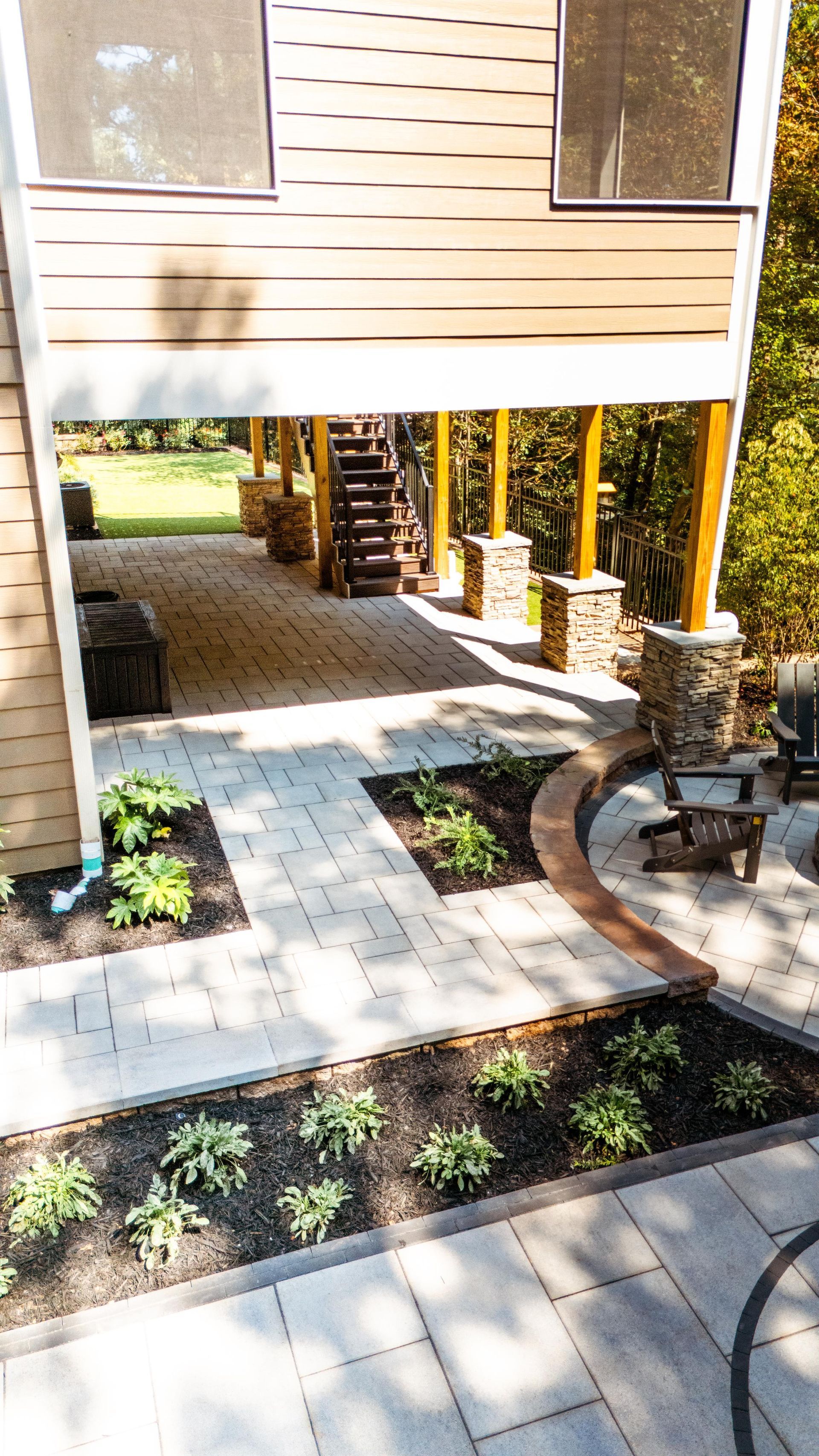 Apartment courtyard with brick paver walkway, small garden beds, and shaded seating area under a building overhang