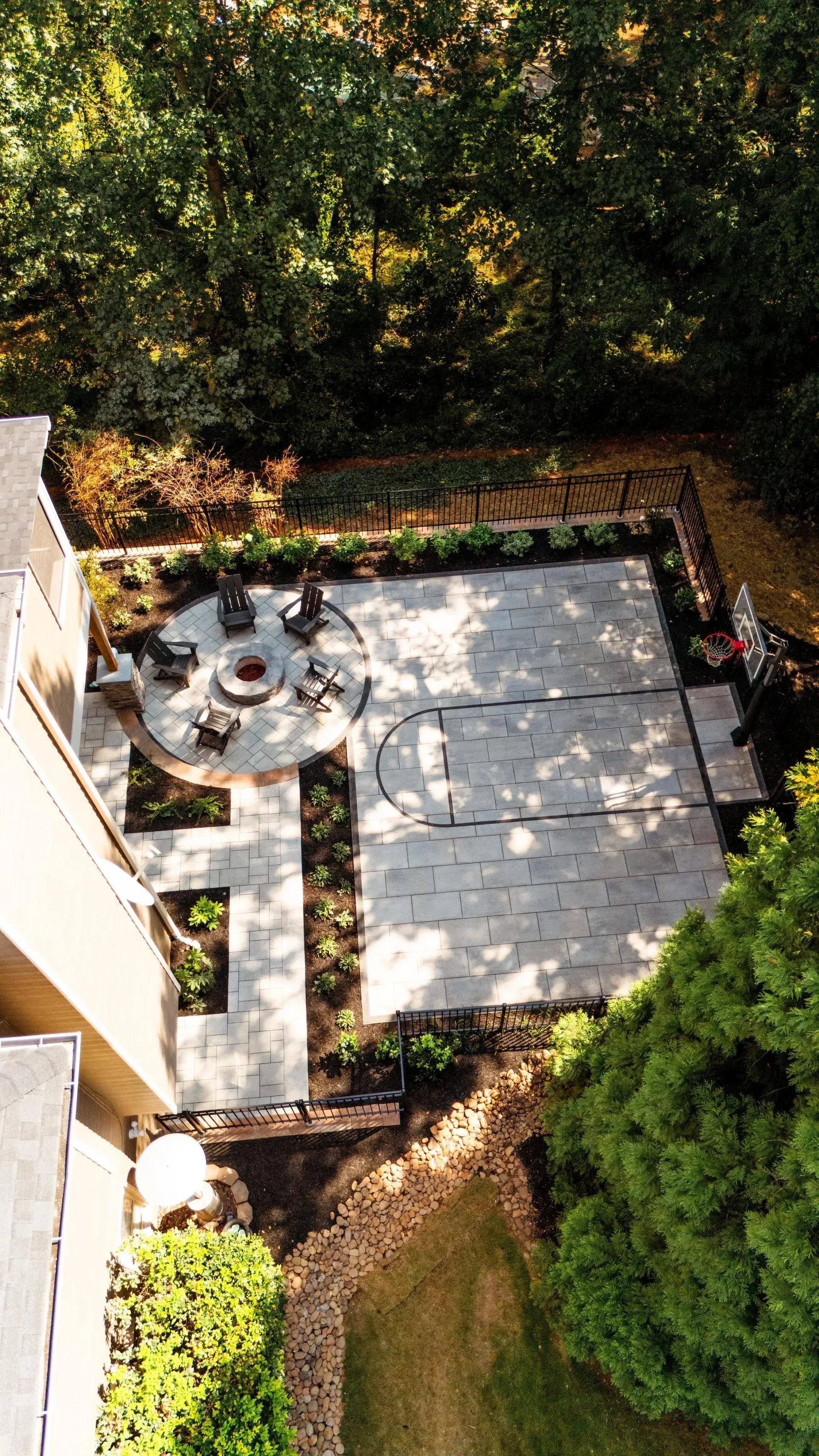 Backyard patio with stone paving, outdoor seating, and dense green hedges around it