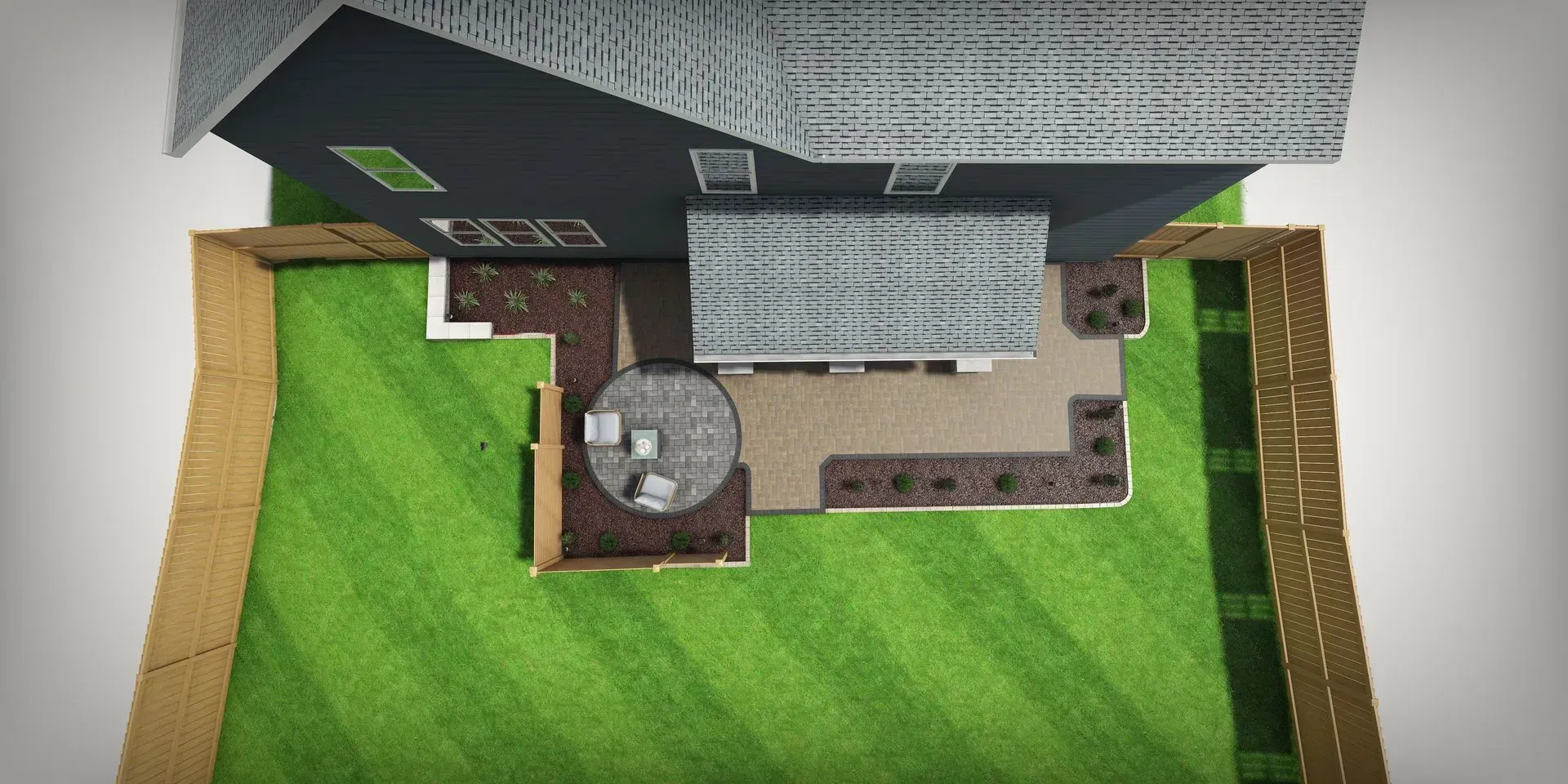Aerial view of a house roof and backyard with green lawn, patio, and circular stone fire pit.