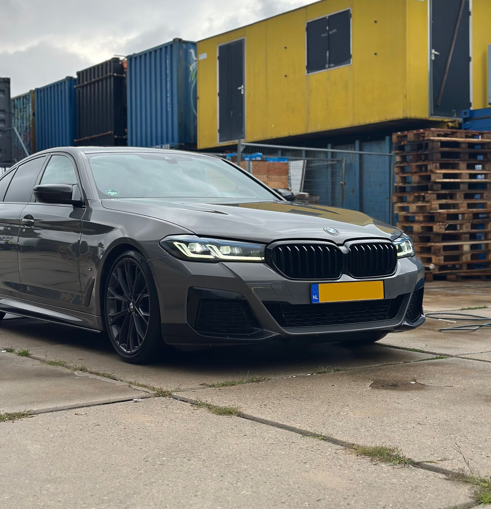 Grijze BMW 5 serie in een industriële omgeving. 