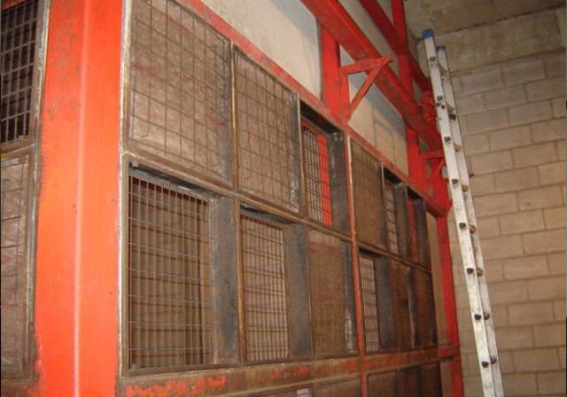 Une échelle est posée à côté d'un mur avec beaucoup de fenêtres.
