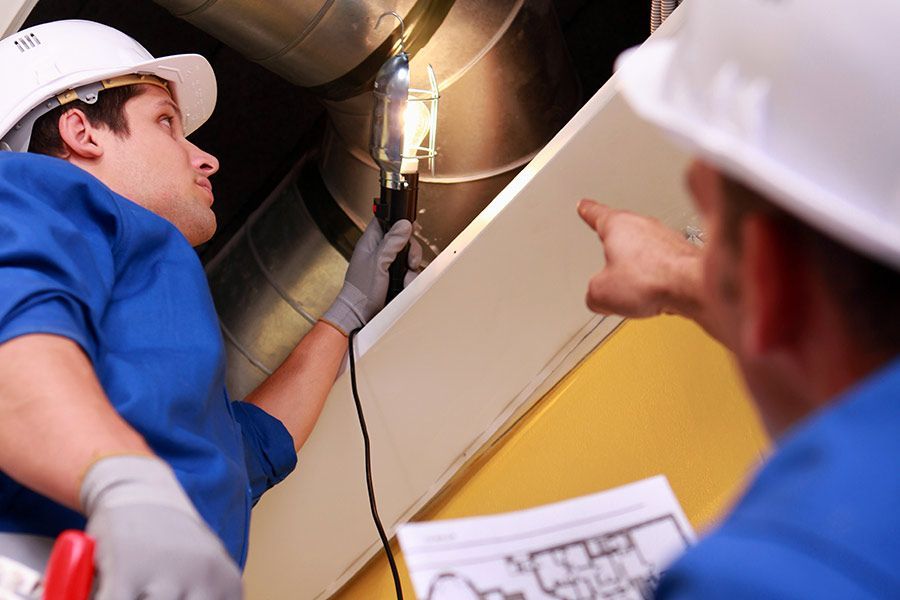 Deux hommes portant des casques de chantier travaillent sur un plafond.