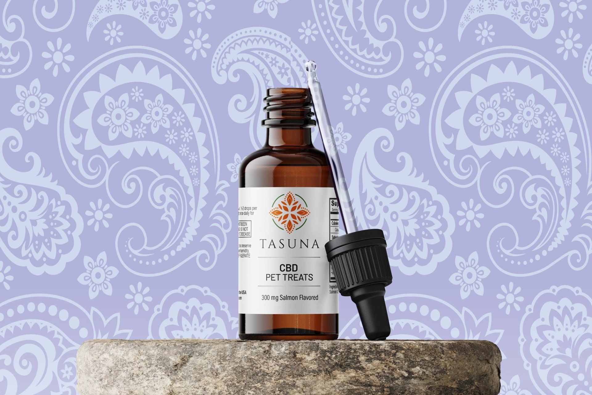 Amber glass bottle of skincare serum with a dropper, set against a lavender paisley pattern background.