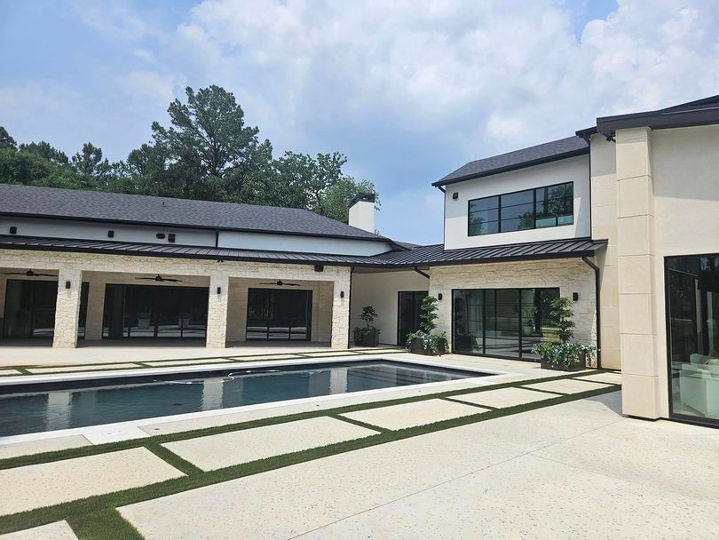 Modern house with a pool and paved courtyard under a partly cloudy sky