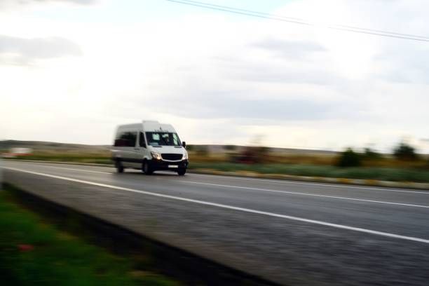Een witte bestelbus rijdt over een wazige snelweg onder een bewolkte hemel.
