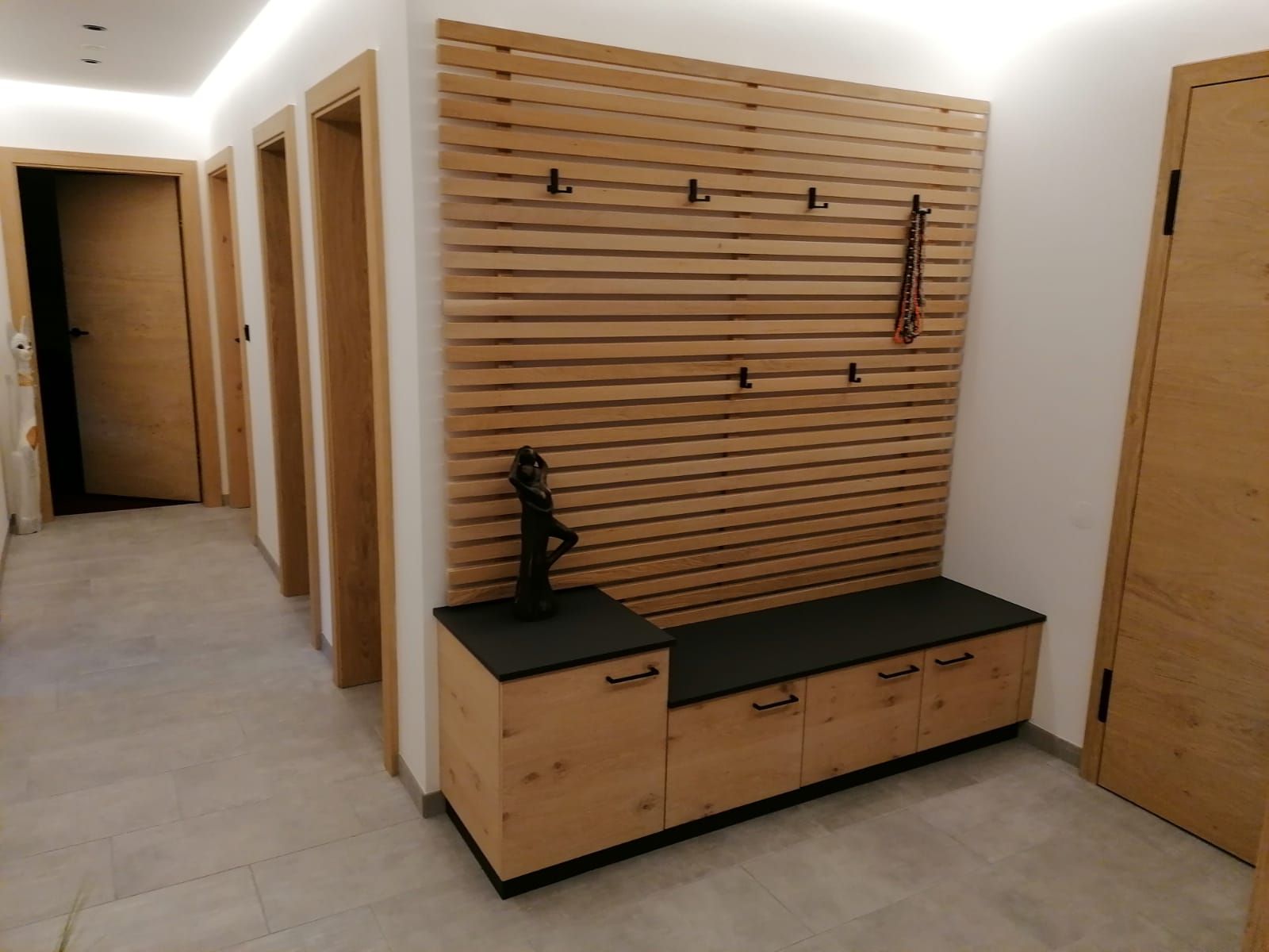 In einem modernen Flur befindet sich eine Wand aus Holzlatten