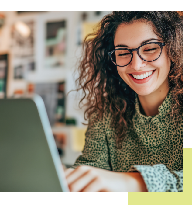 Woman wearing glasses smiles while using a laptop.