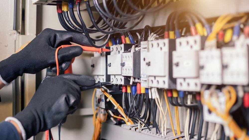 An Electrician Is Working On An Electrical Box With A Multimeter — In Electrics In Babinda, QLD