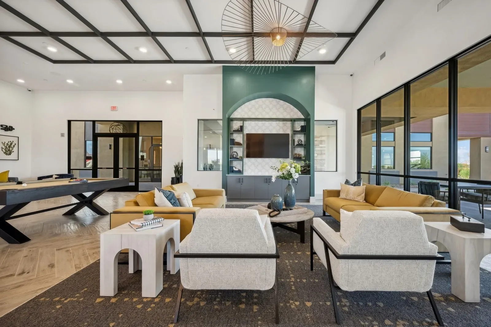 Stylish lounge area with a pool table, comfortable seating, and a large window overlooking an outdoor area  at Longbow Luxury Apartments Mesa, AZ.