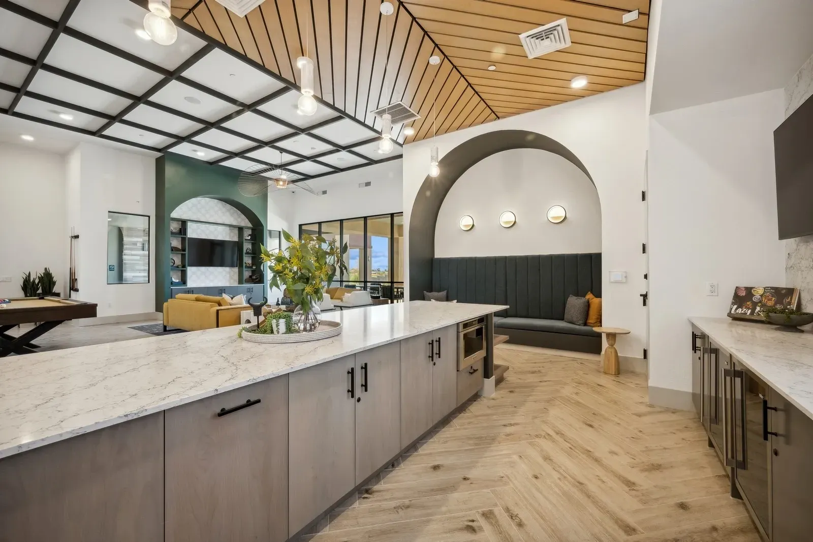 Modern community lounge area with a full-service kitchen island, comfortable seating, and a pool table at Longbow Luxury Apartments Mesa, AZ.