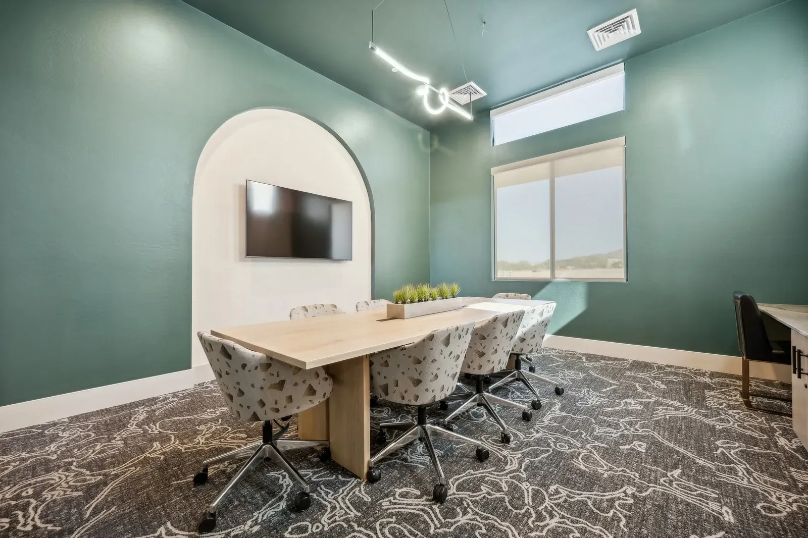 Conference room with large table and chairs, TV on the wall at Longbow Luxury Apartments Mesa, AZ.