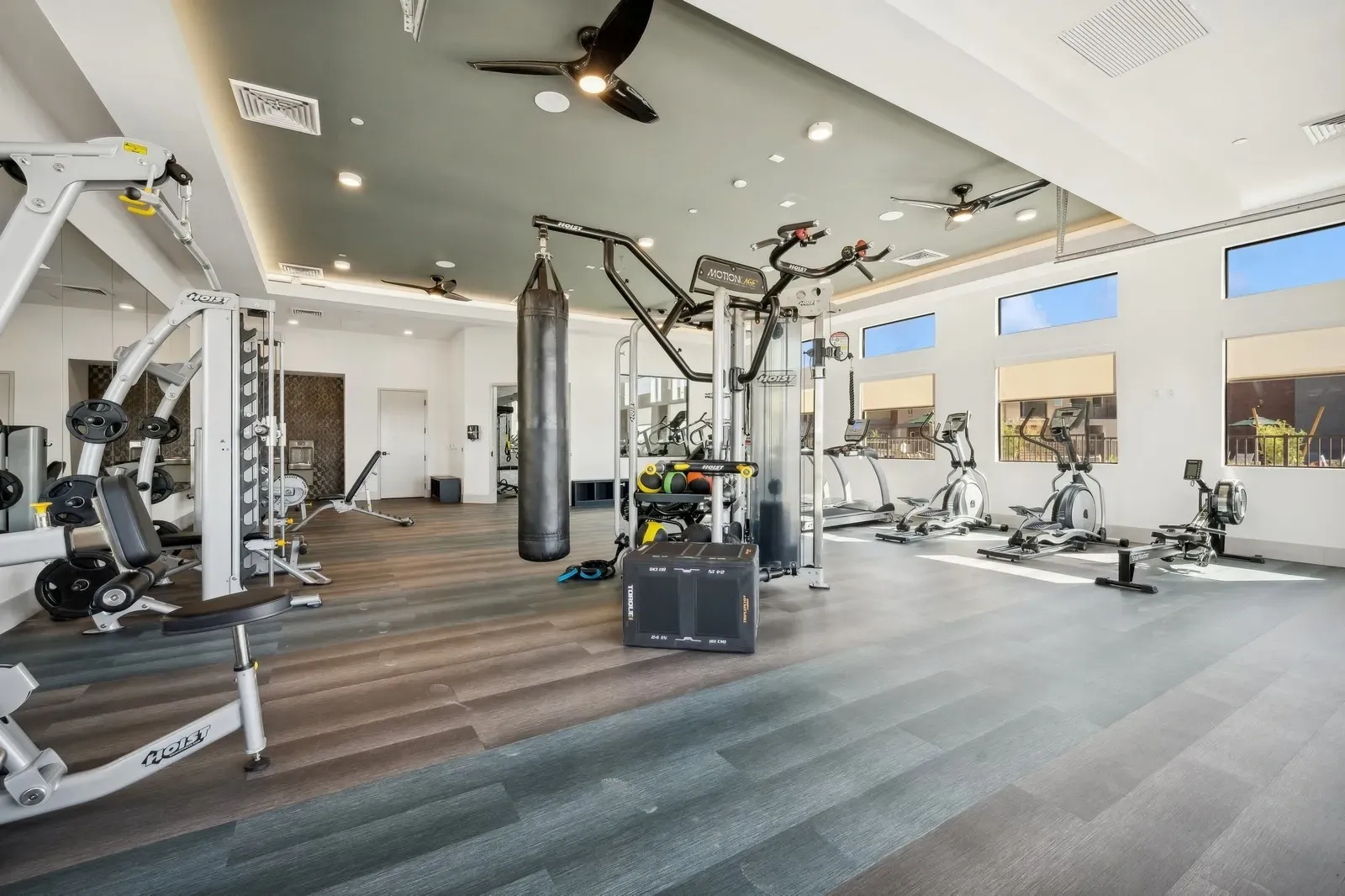 Modern apartment complex gym with treadmills, ellipticals, rowing machine, weight machines, and punching bag  at Longbow Luxury Apartments Mesa, AZ.