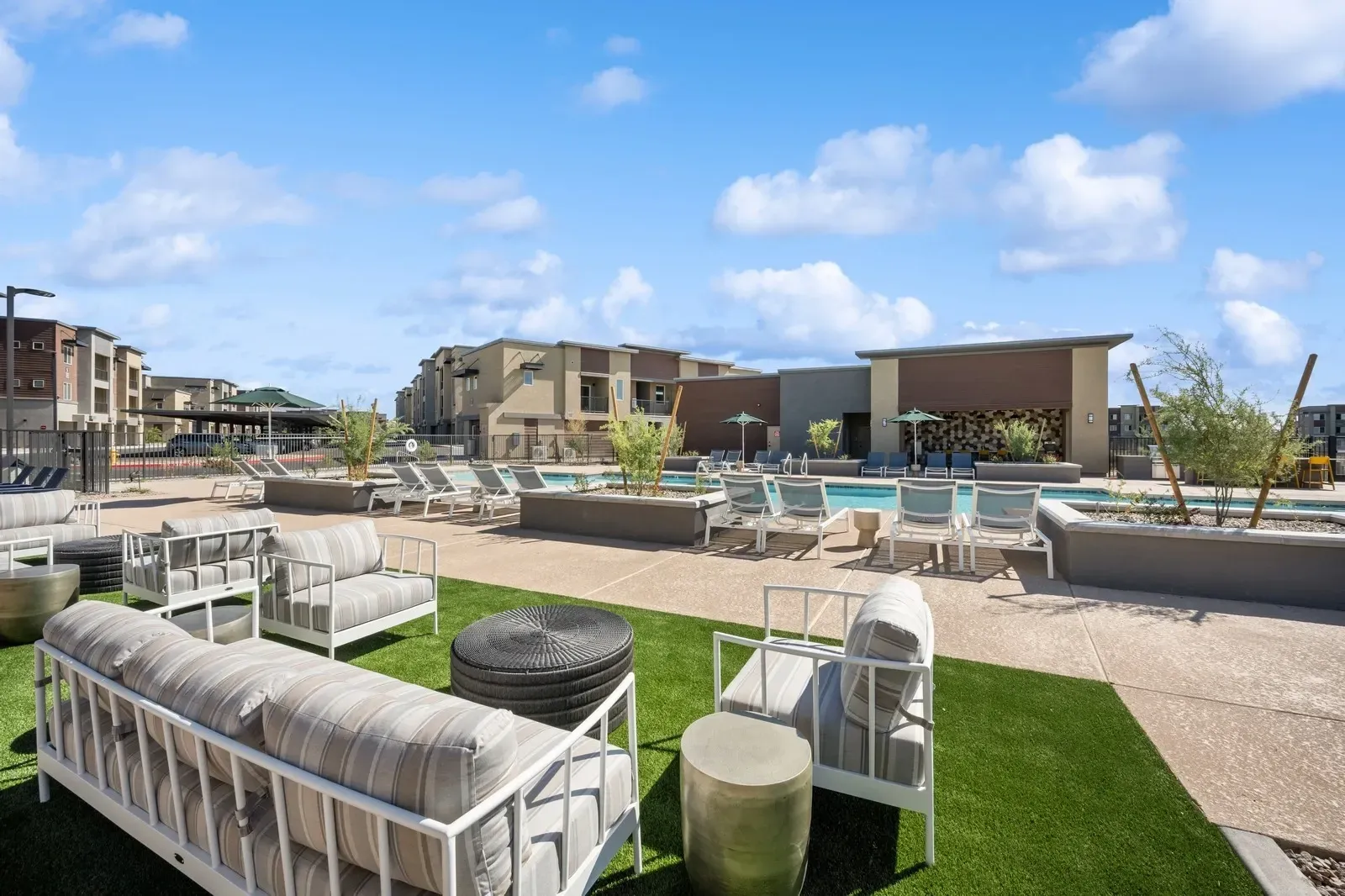 Outdoor lounge area with seating and a swimming pool in the background.